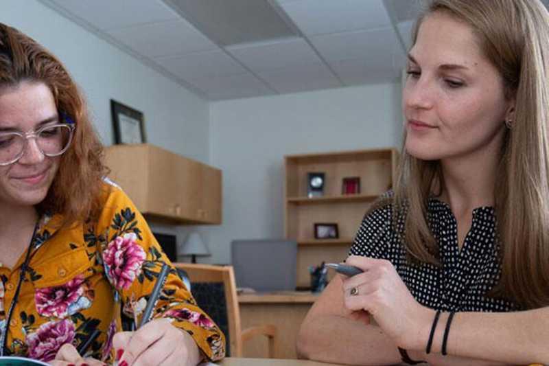 Photo of a Case Western Reserve University student sitting with an advisor, completing paperwork